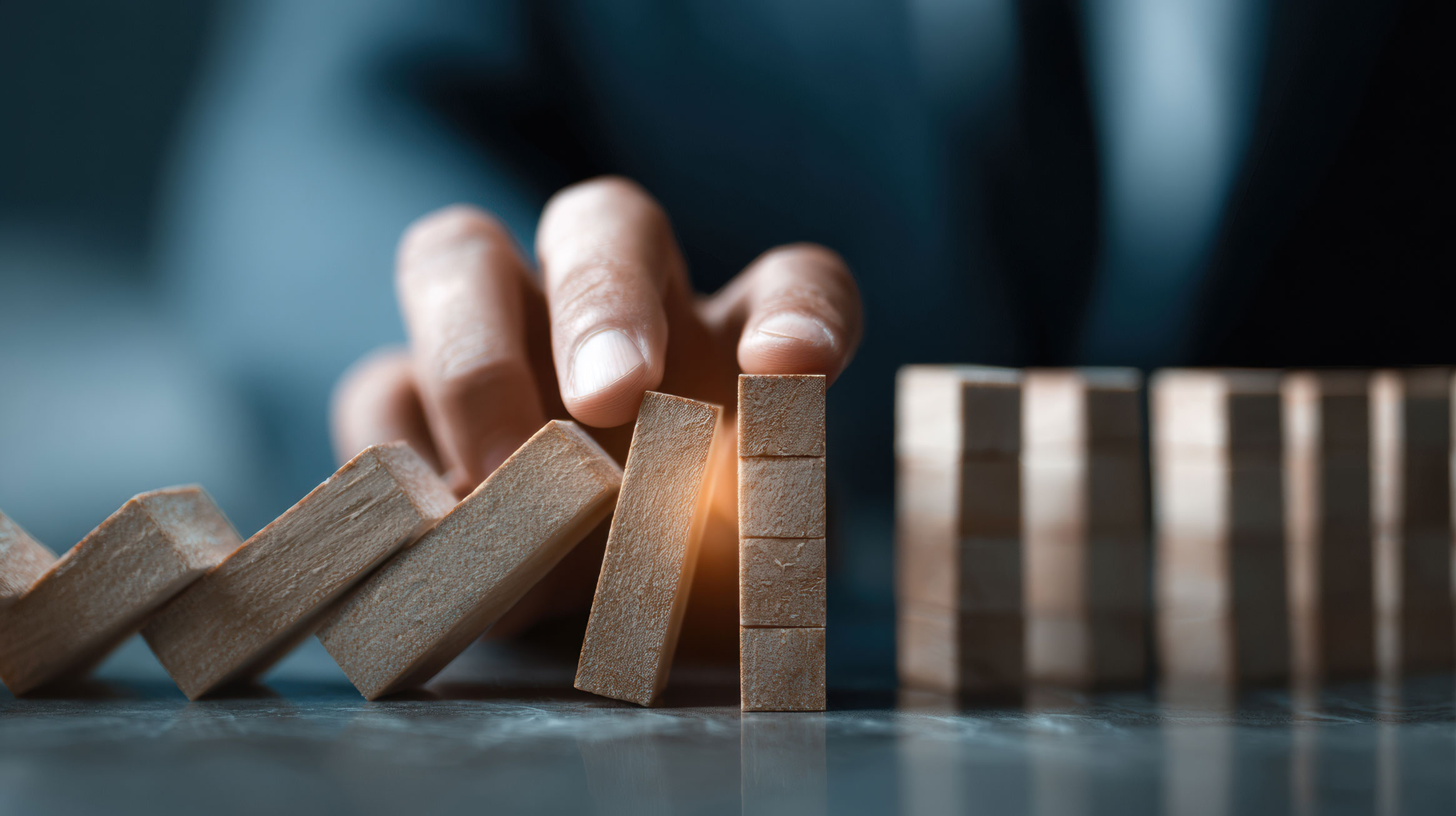 hand preventing dominoes from continuing to fall